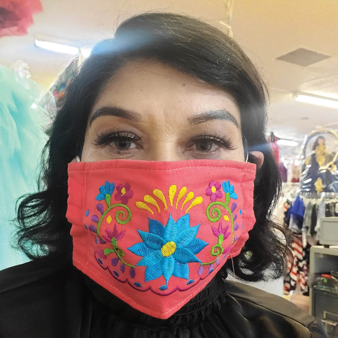 A self-portrait of a woman wearing an elaborately embroidered face mask